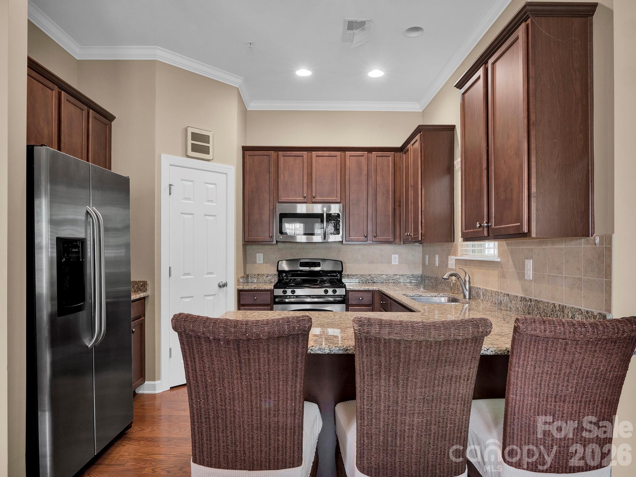 14726 Intermilan Way Charlotte, NC 28277 - Photo 9 of 38 a kitchen with kitchen island granite countertop wooden cabinets a refrigerator a sink a stove and a oven