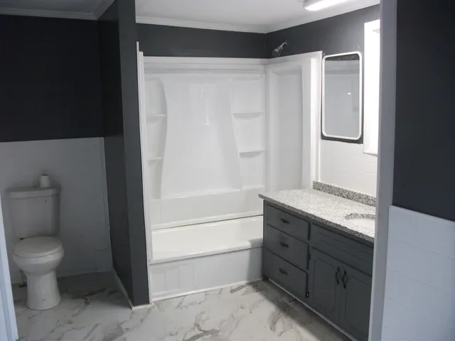 a bathroom with a granite countertop sink a toilet and shower