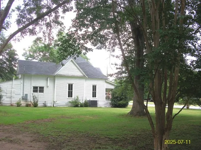 a view of a yard in front of a house with a large tree