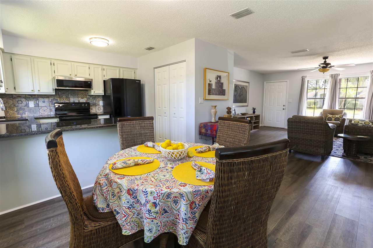 162 Segovia Road St. Augustine, FL 32086 - Photo 11 of 29 a kitchen with granite countertop a dining table chairs sink refrigerator and microwave