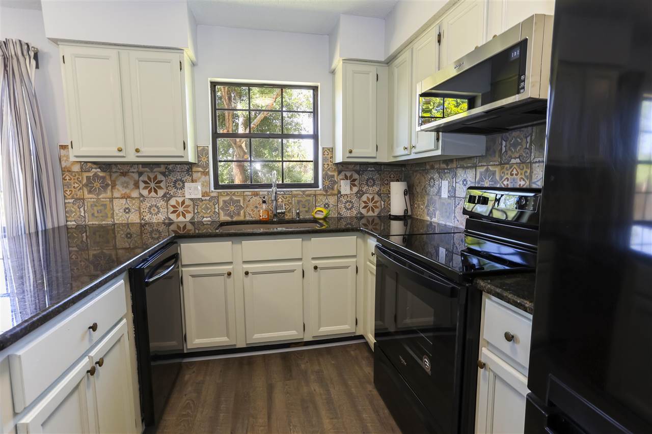 162 Segovia Road St. Augustine, FL 32086 - Photo 10 of 29 a kitchen with stainless steel appliances granite countertop a sink a stove cabinets and a wooden floor