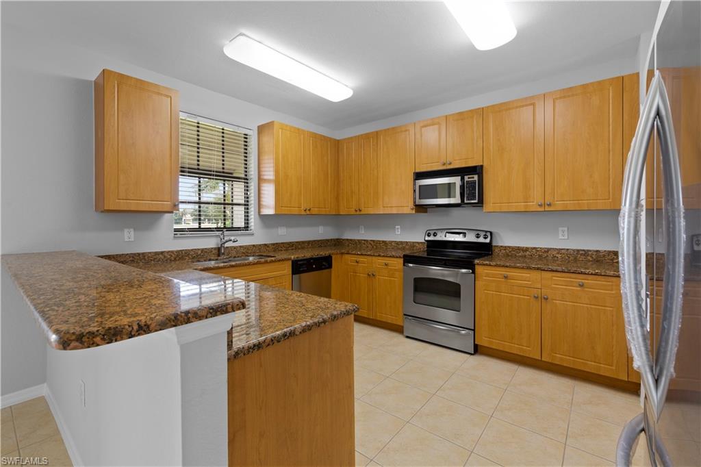 15243 Summit Pl Circle, Unit 247 Naples, FL 34119 - Photo 5 of 18 a kitchen with stainless steel appliances granite countertop a stove a sink and a microwave