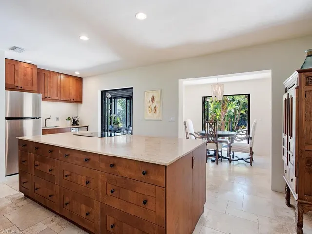 a living room with stainless steel appliances kitchen island granite countertop a refrigerator a sink dishwasher a dining table and chairs with wooden floor