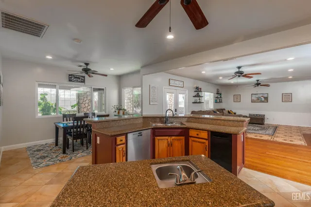 a kitchen with stainless steel appliances granite countertop a refrigerator a stove and a sink with wooden floor