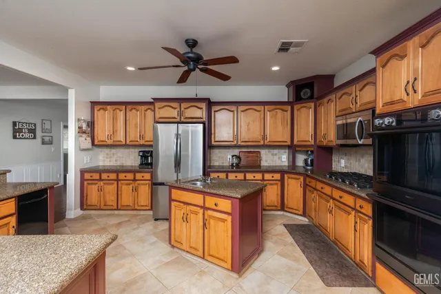 a kitchen with stainless steel appliances granite countertop a stove top oven and a refrigerator
