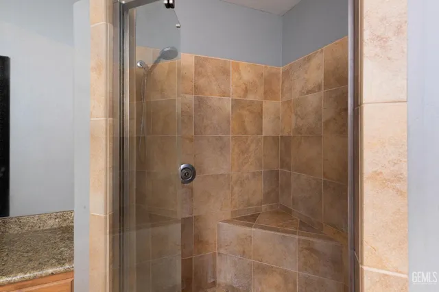 a bathroom with a granite countertop sink a mirror and shower