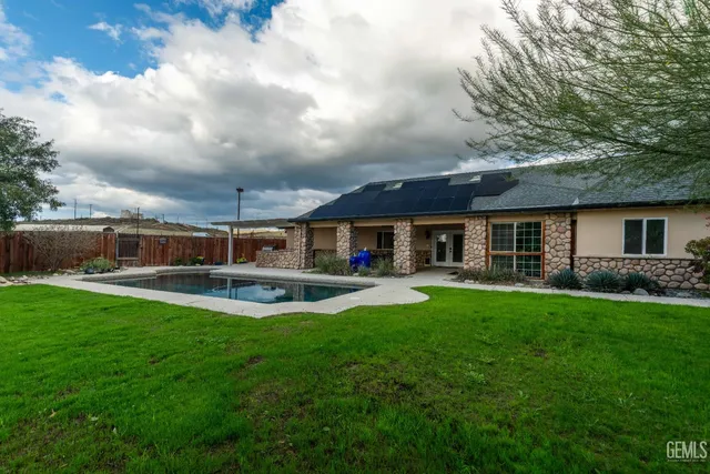 a kitchen with granite countertop a refrigerator a stove top oven a chimney wooden floor and cabinets