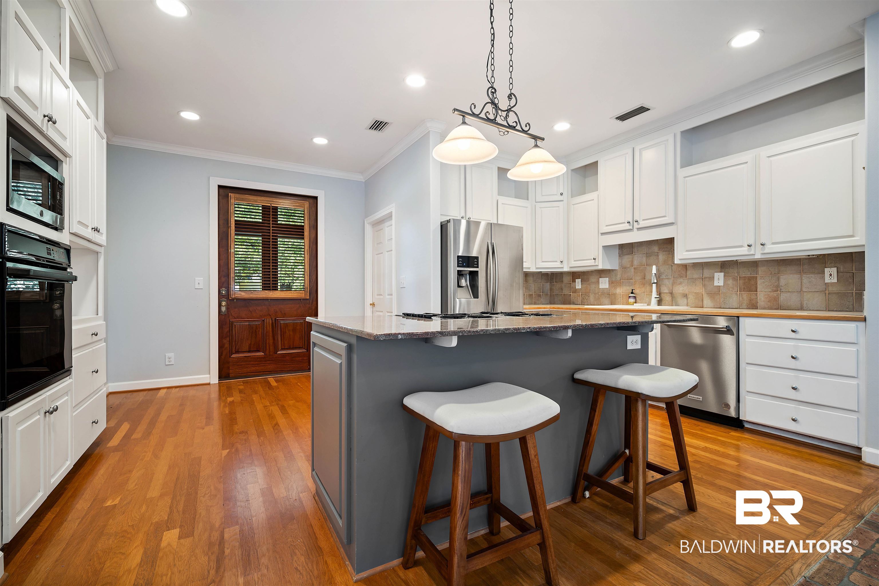 204 General Canby Loop Daphne, AL 36527 - Photo 10 of 36 Kitchen featuring a kitchen island, decorative light fixtures, white cabinetry, appliances with stainless steel finishes, and hardwood / wood-style floors