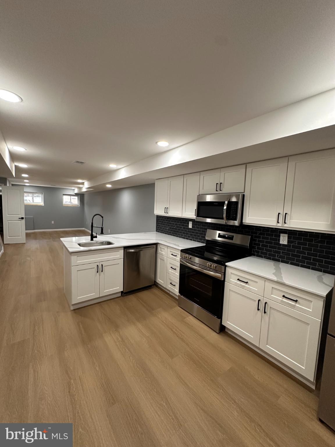 1927 Druid Hill Avenue Baltimore, MD 21217 - Photo 4 of 10 a large white kitchen with a stove a sink and a microwave
