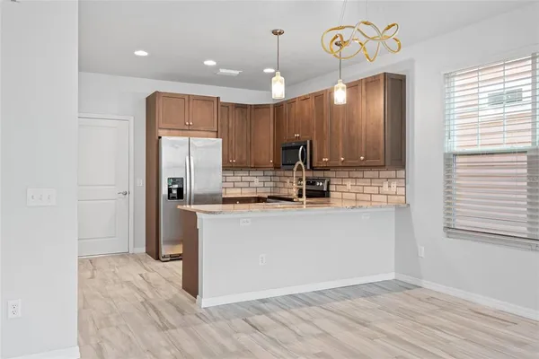 a kitchen with kitchen island granite countertop wooden cabinets and refrigerator