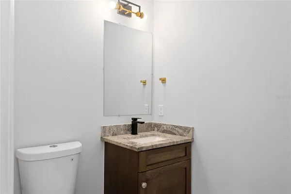 a bathroom with a granite countertop sink and a toilet