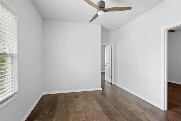 an empty room with wooden floor fan and windows