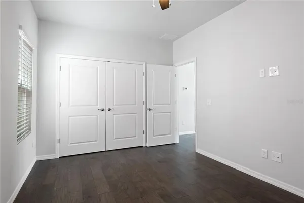 an empty room with wooden floor and windows with curtains