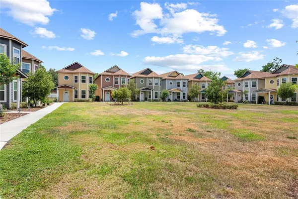 a view of a big house with a big yard and large trees