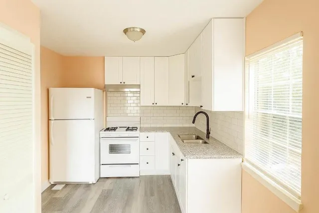 a kitchen with a refrigerator a stove a sink dishwasher and white countertops with wooden floor