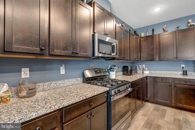 a kitchen with granite countertop stainless steel appliances a stove a sink and cabinets
