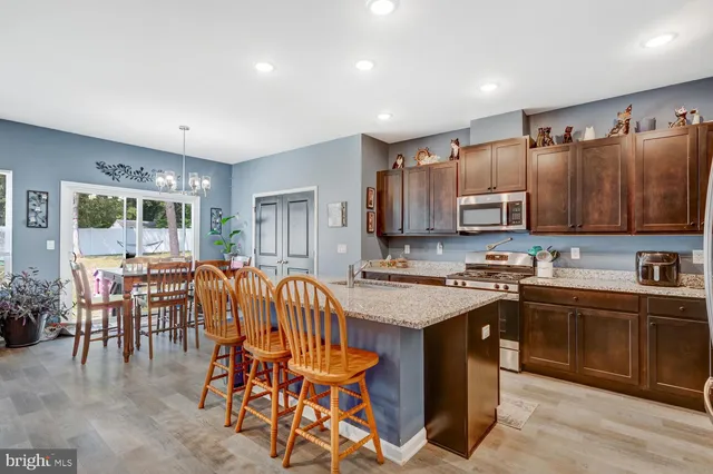 a kitchen with stainless steel appliances granite countertop a table chairs sink and cabinets