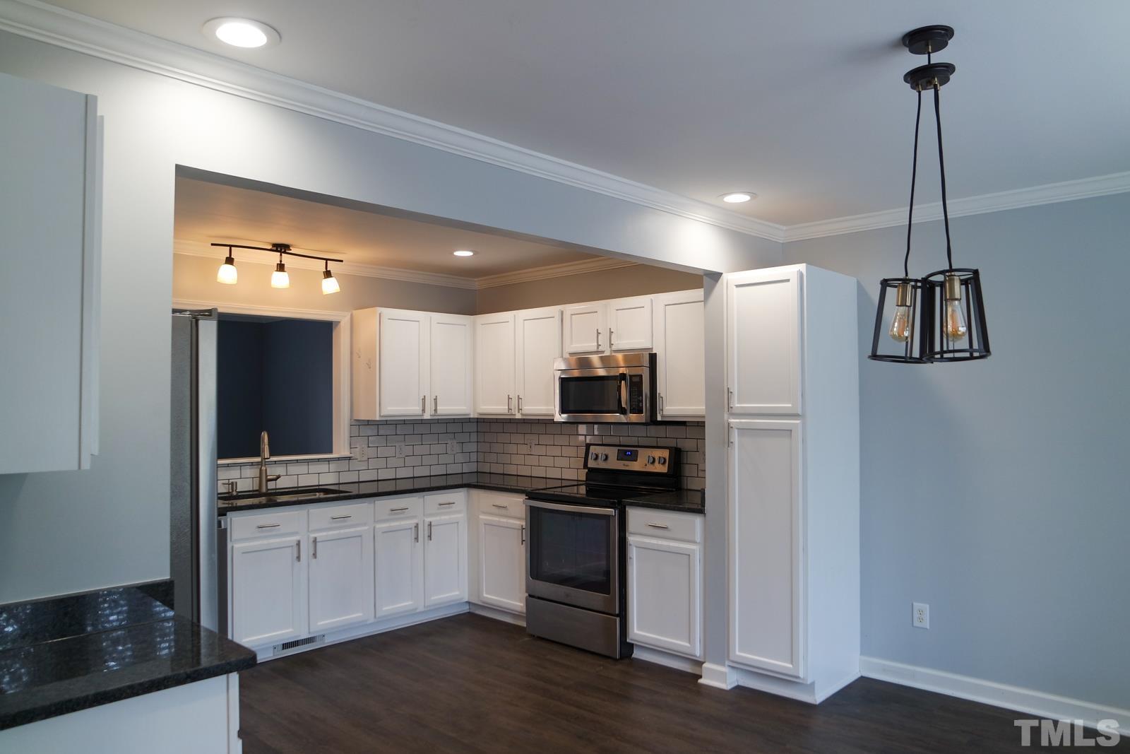 3800 Axle Lane Raleigh, NC 27616 - Photo 3 of 11 a kitchen with stainless steel appliances kitchen island granite countertop a refrigerator a sink dishwasher a stove and white cabinets with wooden floor
