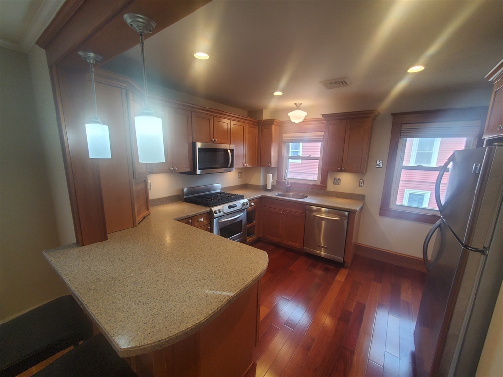 1 Grayson Street, Unit 2 Boston, MA 02124 - Photo 2 of 23 a kitchen with a sink a stove a refrigerator a oven a dining table and chairs