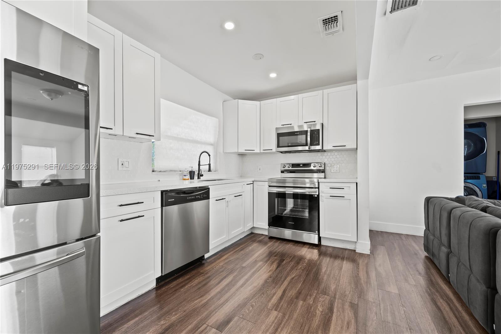 919 Northwest 66th Street Miami, FL 33150 - Photo 4 of 21 a kitchen with white cabinets and stainless steel appliances