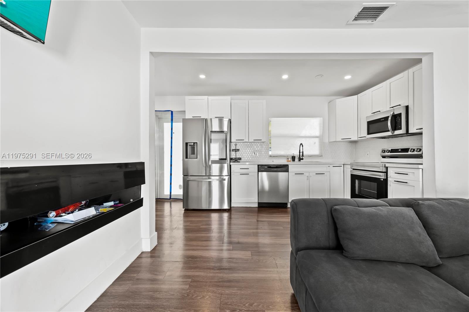 919 Northwest 66th Street Miami, FL 33150 - Photo 6 of 21 a living room with stainless steel appliances furniture a fireplace a flat screen tv and a kitchen view