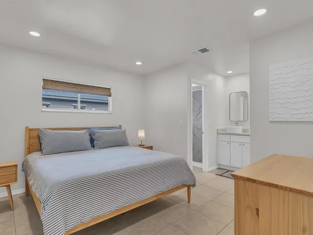 a bedroom with a large bed a rug and painting on the wall