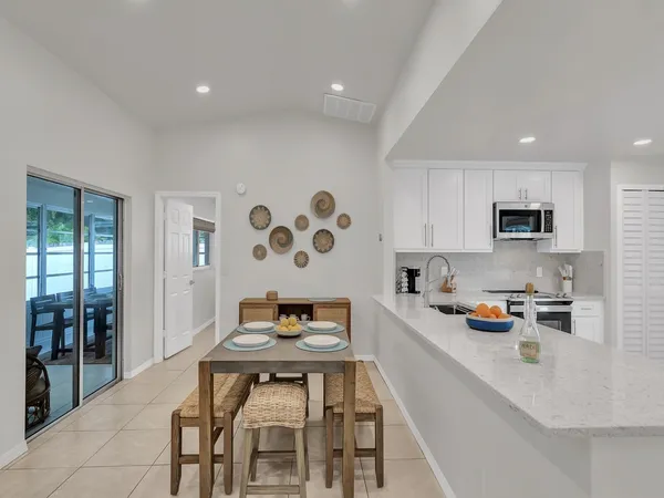 a kitchen with stainless steel appliances a dining table and chairs with wooden floor