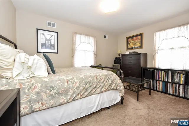 a bedroom with a bed painting on wall and a window