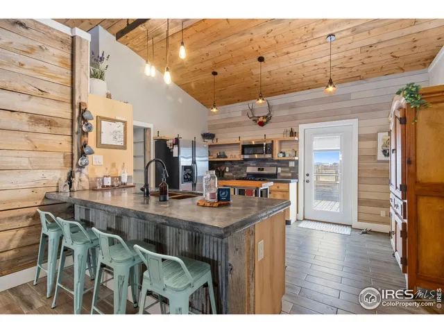 a kitchen with stainless steel appliances kitchen island granite countertop a refrigerator a stove a sink dishwasher and white cabinets with wooden floor