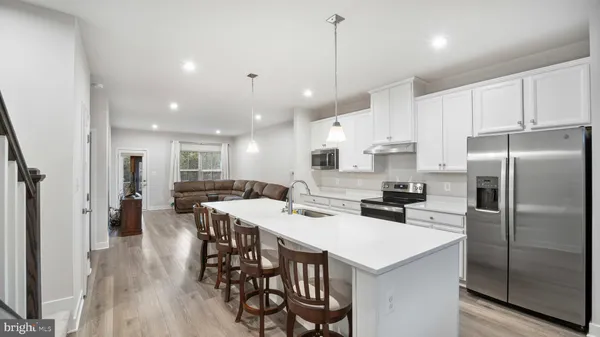 a kitchen with stainless steel appliances a dining table chairs stove refrigerator and cabinets