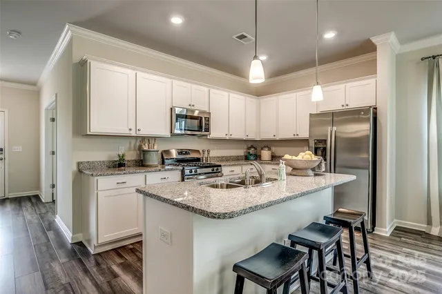 a kitchen with stainless steel appliances granite countertop a sink a stove a refrigerator cabinets and chairs