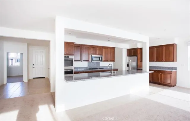 a large white kitchen with stainless steel appliances kitchen island granite countertop a refrigerator and a stove top oven