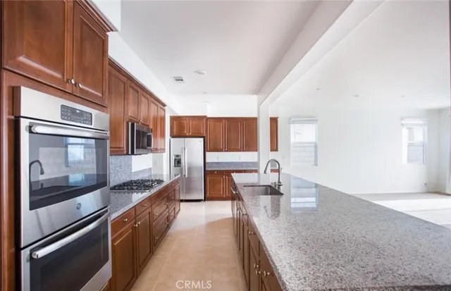 a large kitchen with stainless steel appliances granite countertop a lot of counter space and wooden floors