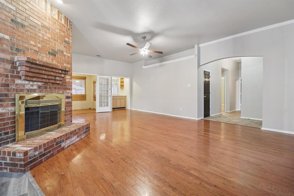 600 North Chattey Road DeSoto, TX 75115 - Photo 10 of 40 an empty room with wooden floor fireplace and a kitchen view
