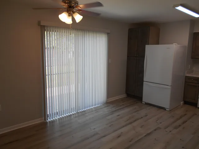 an empty room with wooden floor cabinet and windows