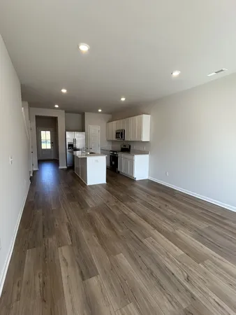 a view of kitchen with kitchen island wooden floor center island and stainless steel appliances
