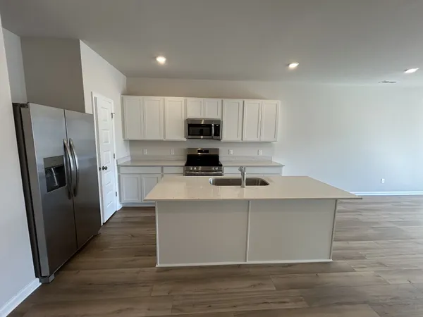 a kitchen with stainless steel appliances a stove a sink a refrigerator a microwave and cabinets