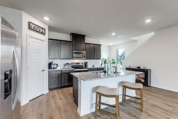 a kitchen with stainless steel appliances granite countertop a sink a stove a microwave a refrigerator and island