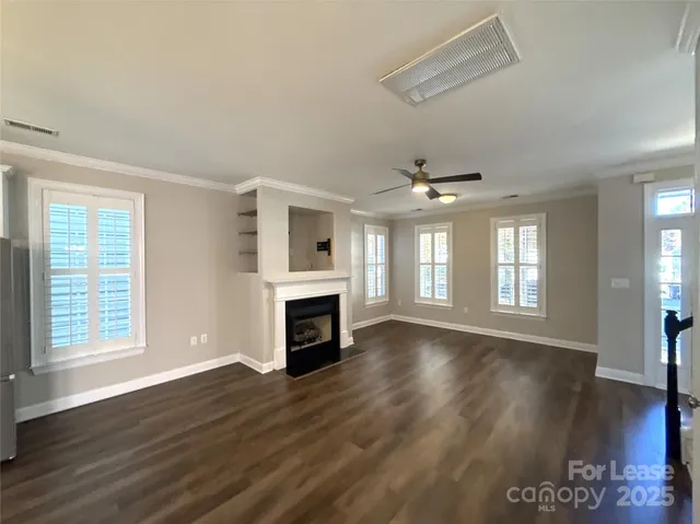 an empty room with wooden floor fireplace and windows