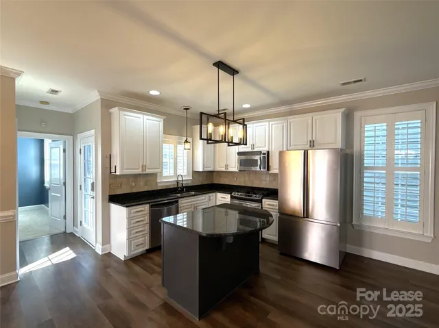 a kitchen with stainless steel appliances granite countertop a refrigerator a sink dishwasher a stove and white countertops with wooden floor