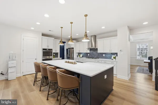 a large kitchen with kitchen island a stove a sink a oven and a dining table with wooden floor