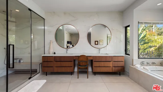 a bathroom with a tub a double vanity sink and a mirror