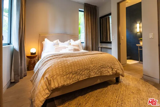 a large bed sitting in a bedroom next to a window and a chandelier