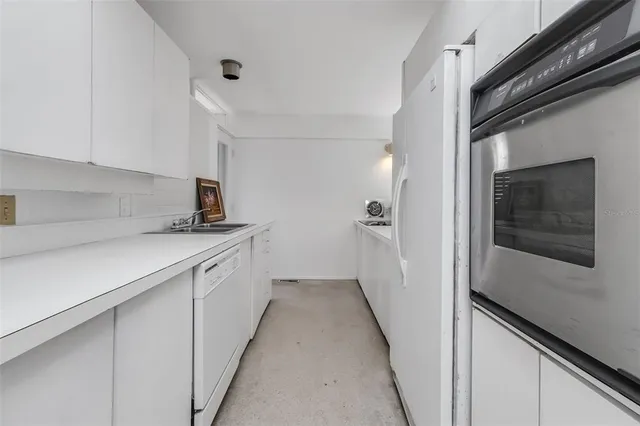 a hallway with white cabinets and white appliances