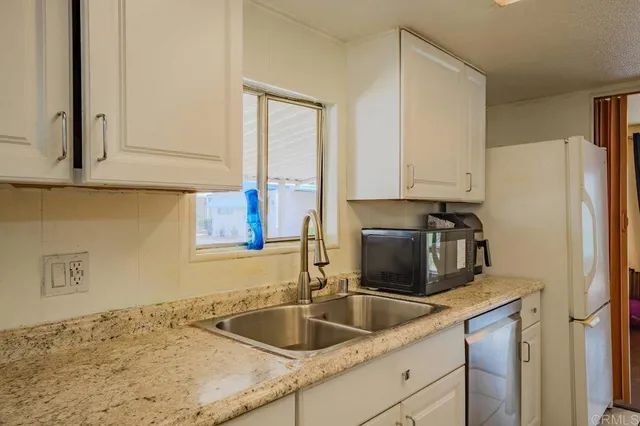 a kitchen with granite countertop a sink and a refrigerator
