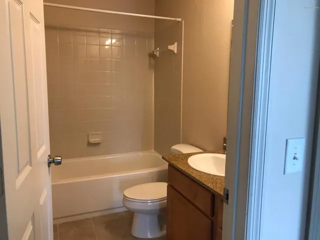 a bathroom with a granite countertop toilet a sink and bathtub
