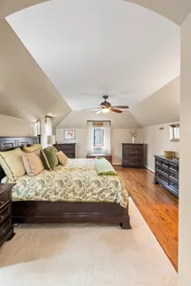 a bed sitting in a spacious bedroom next to a larger window with kitchen view