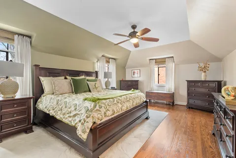 a spacious bedroom with a bed a dresser and wooden floor