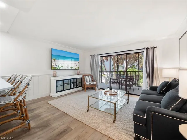 a living room with furniture a rug a lamp and a large window