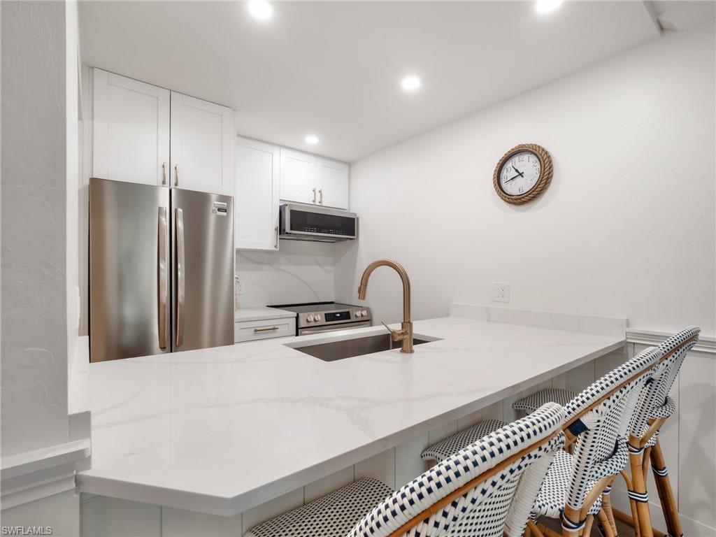 3113 Tennis Villas Captiva, FL 33924 - Photo 21 of 48 a kitchen with stainless steel appliances a sink a stove a refrigerator with white cabinets and wooden floor